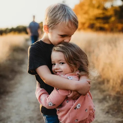 Boy hugs his sister while walking in nature